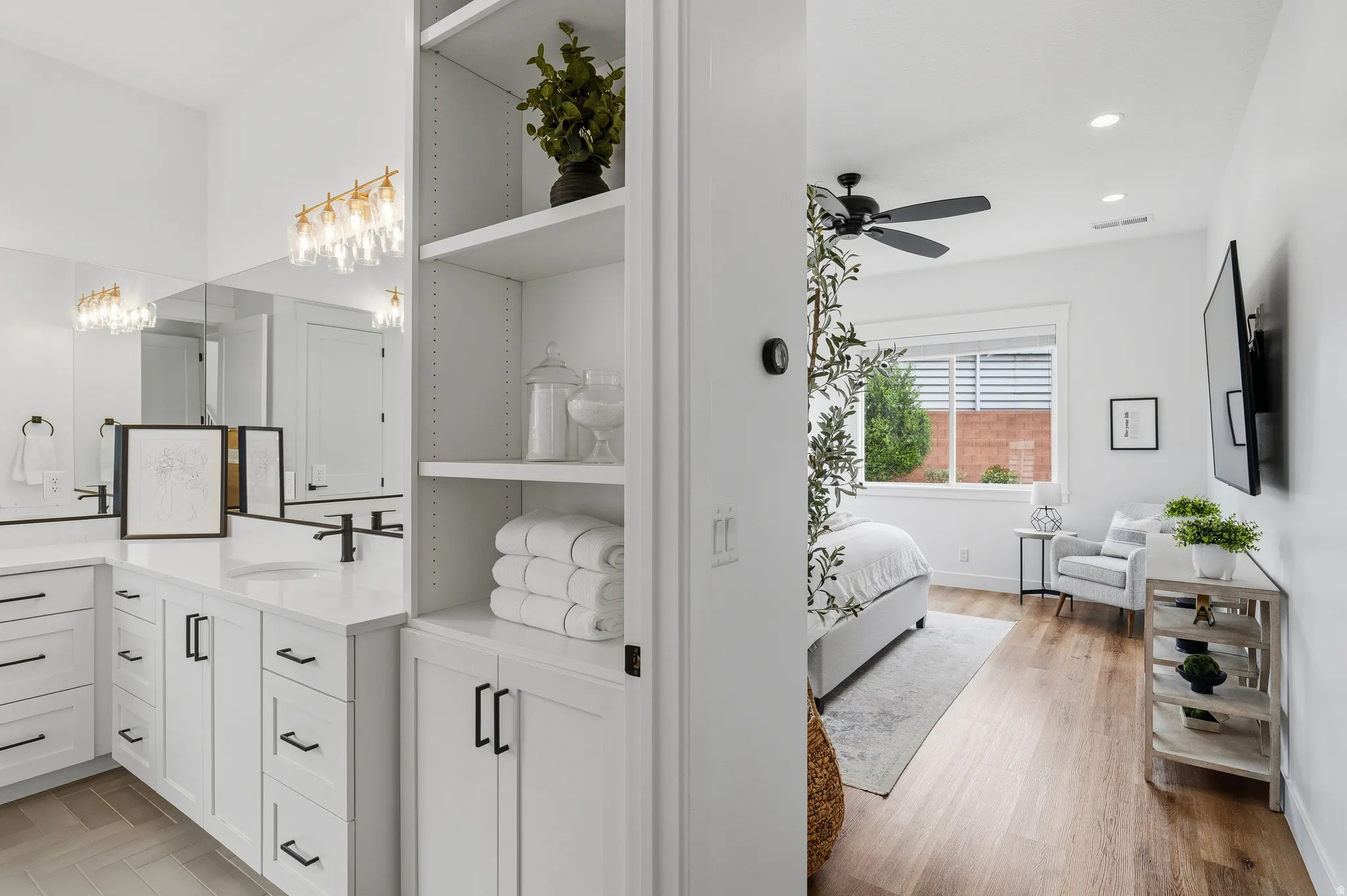 Contemporary vanity with dual sinks, white cabinetry, and matte black fixtures, complemented by a built-in shelving unit.