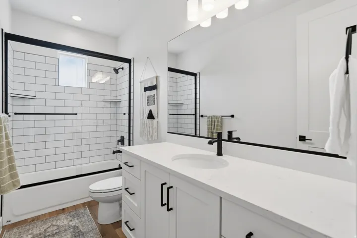 White subway tile shower surround with black-framed glass enclosure.