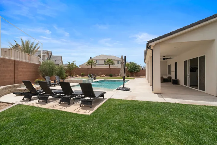 Expansive outdoor living area featuring a swimming pool, integrated spa, and concrete patio.
