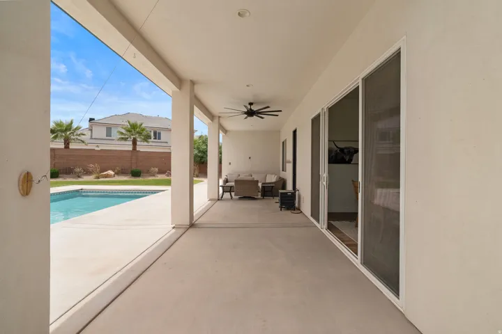 Covered patio with a concrete surface, featuring a ceiling fan, recessed lighting, and multiple sliding glass doors.