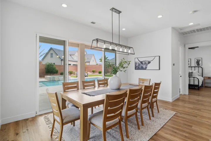 Spacious dining area featuring wood-finish flooring and a contemporary linear chandelier.