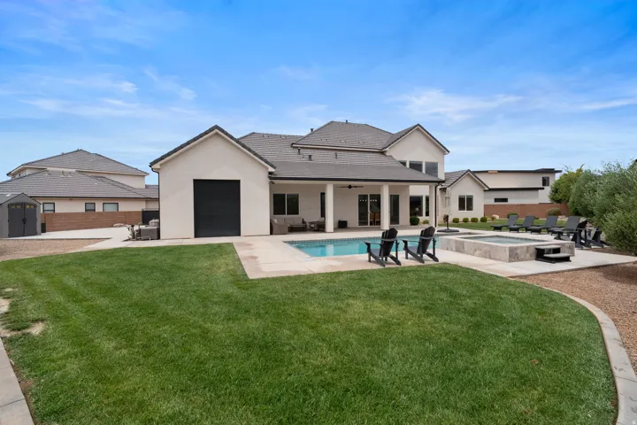 Expansive rear yard featuring a rectangular swimming pool, integrated spa, and a concrete patio surround.