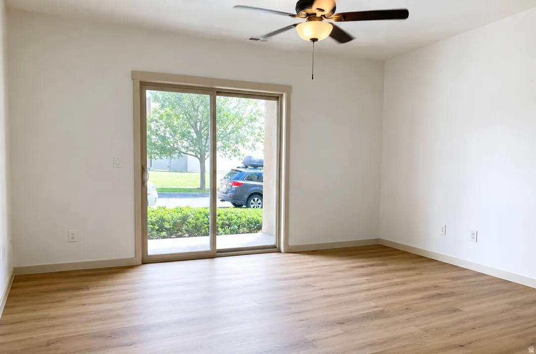 Spacious interior featuring wood-finish flooring and a ceiling fan with integrated lighting