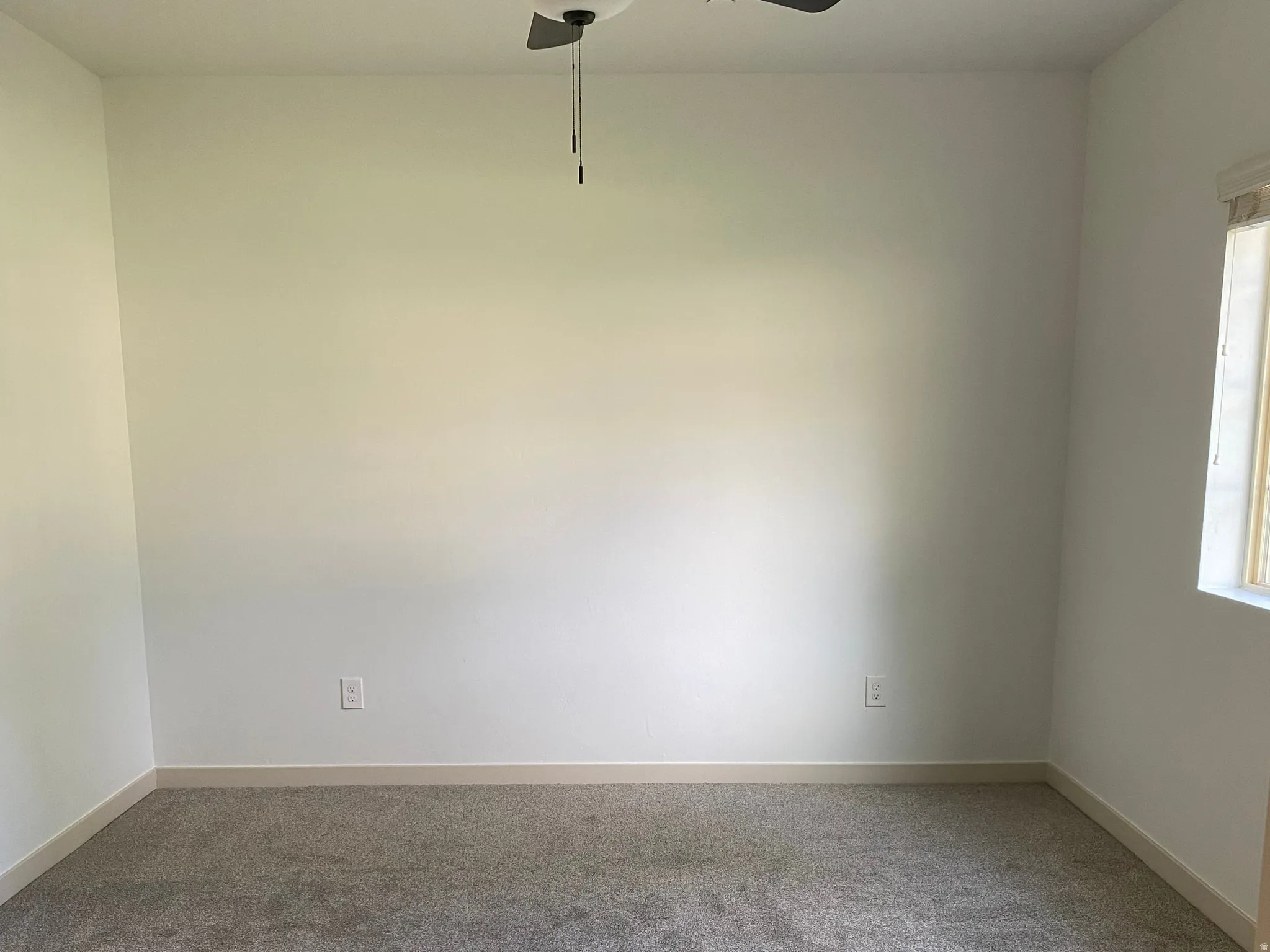 Neutral wall color, wall-to-wall carpeting, ceiling fan with integrated lighting, window with natural light, and baseboard molding