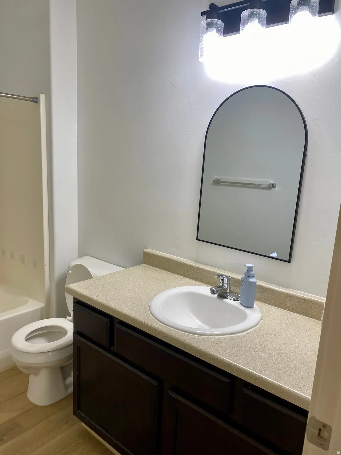 Bathroom vanity featuring an integrated white sink, chrome faucet, and dark wood-finish cabinetry