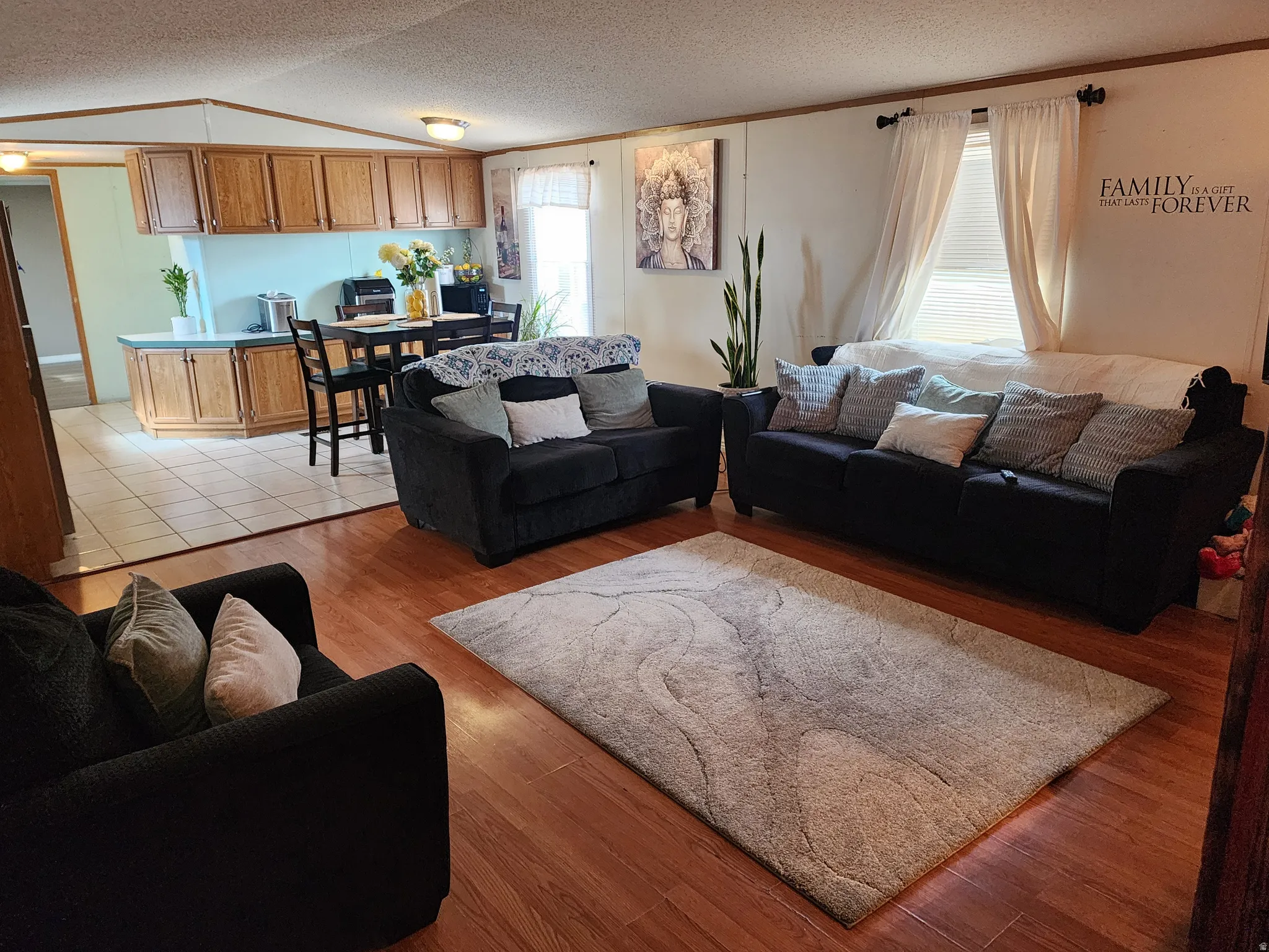 Living area featuring wood-finish flooring, a rectangular window with blinds and drapes, and recessed lighting