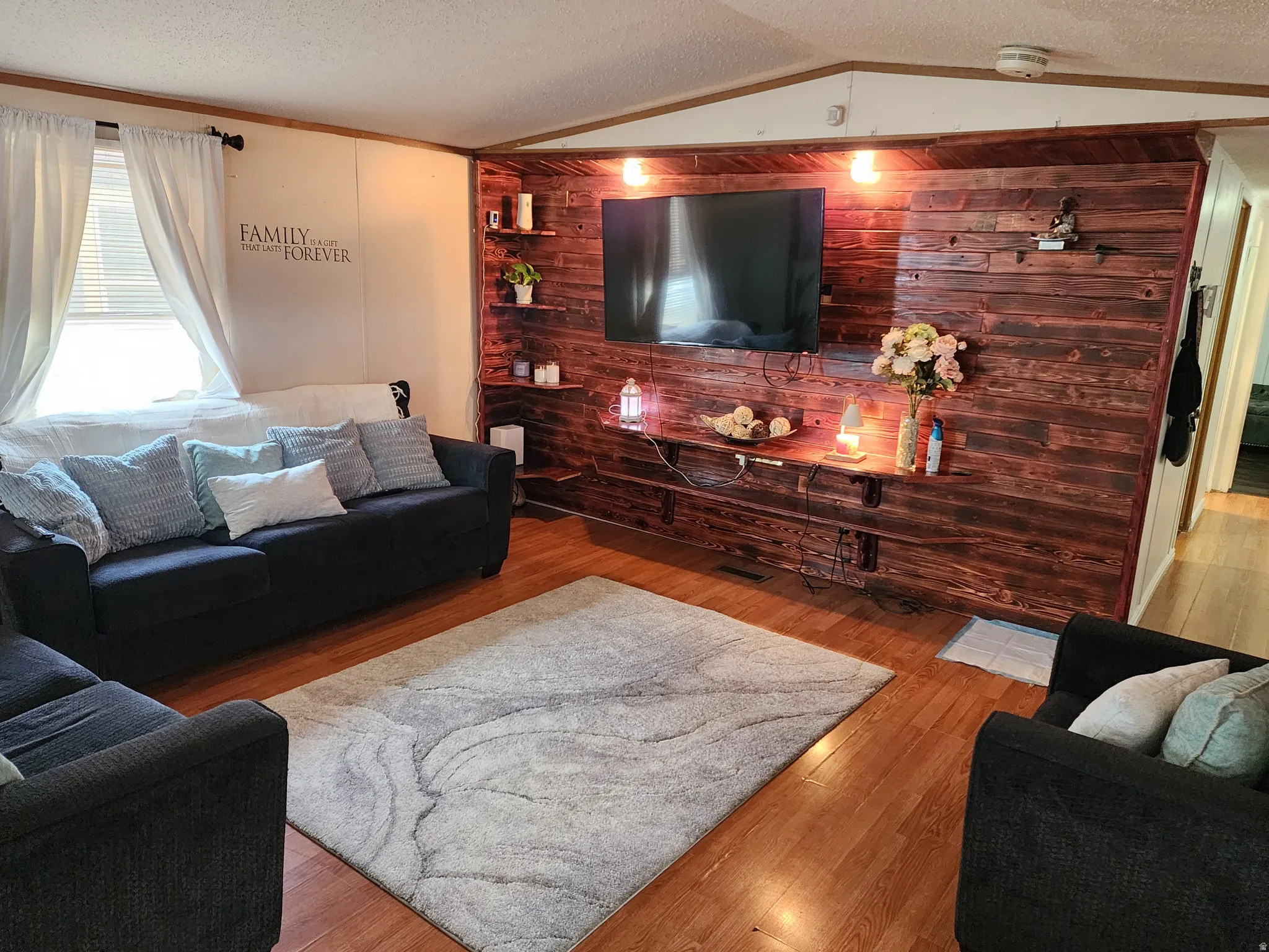 Living area featuring wood-finish flooring and a decorative accent wall with built-in shelving
