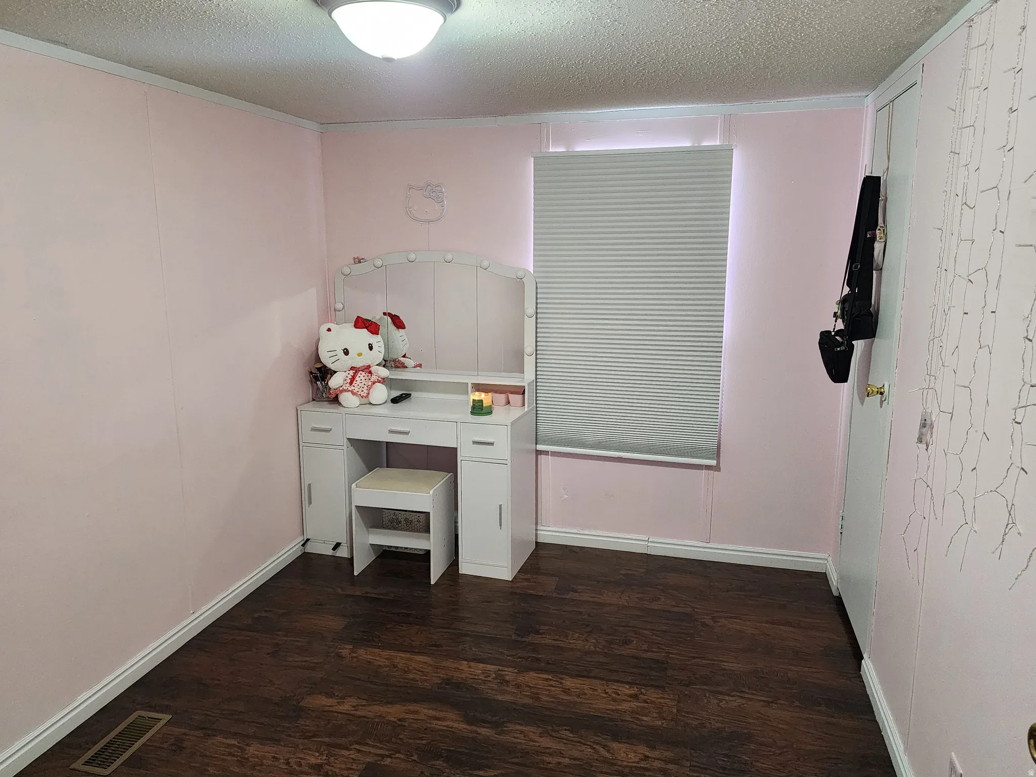 Room featuring wood-finish flooring, a ceiling-mounted light fixture, and a window with a cellular blind