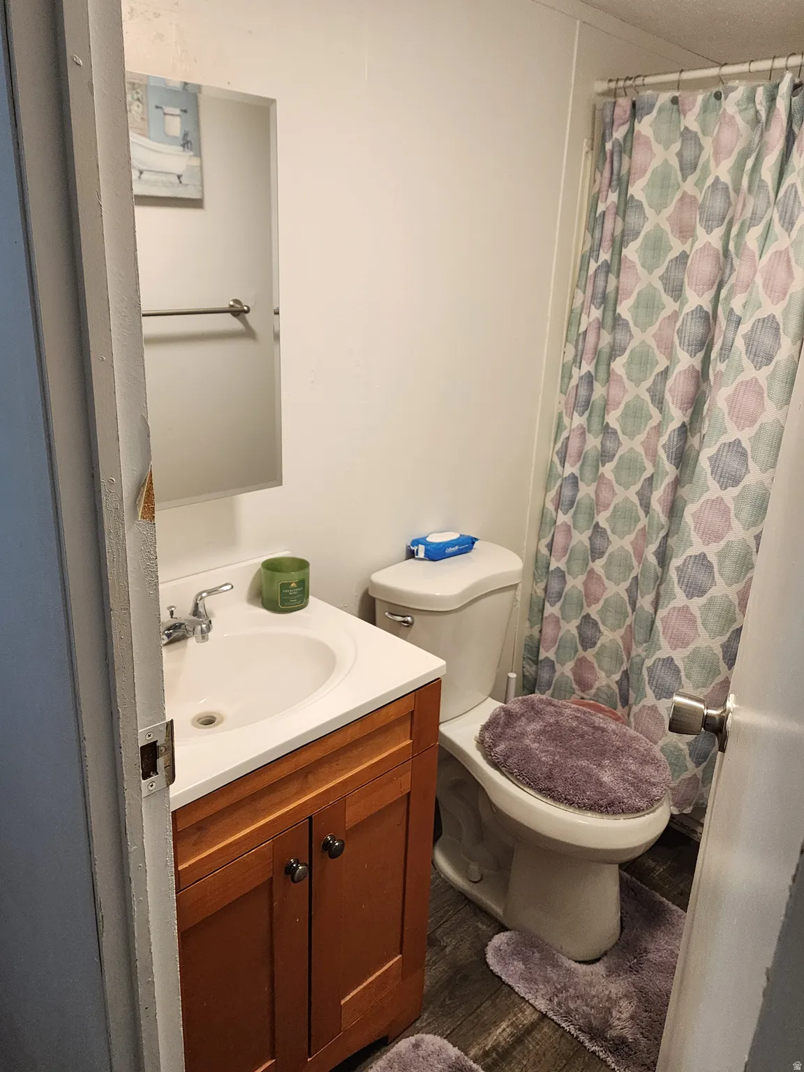 Compact bathroom featuring a single vanity with wood-finish cabinetry, a white countertop, and a basin sink with a chrome faucet