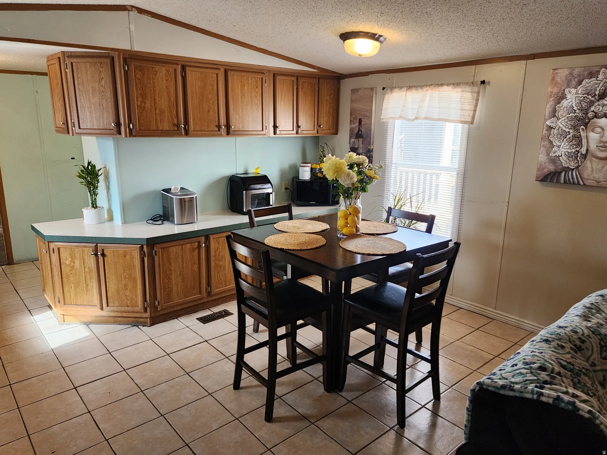 Kitchen area featuring wood cabinetry, light countertops, and a tile floor