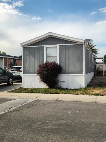Single-story manufactured home featuring gray vertical siding and white trim