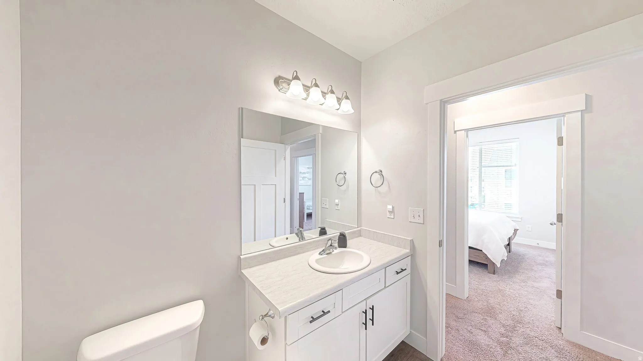 Bathroom featuring a white vanity with an integrated sink, a large wall-mounted mirror, and a three-light fixture