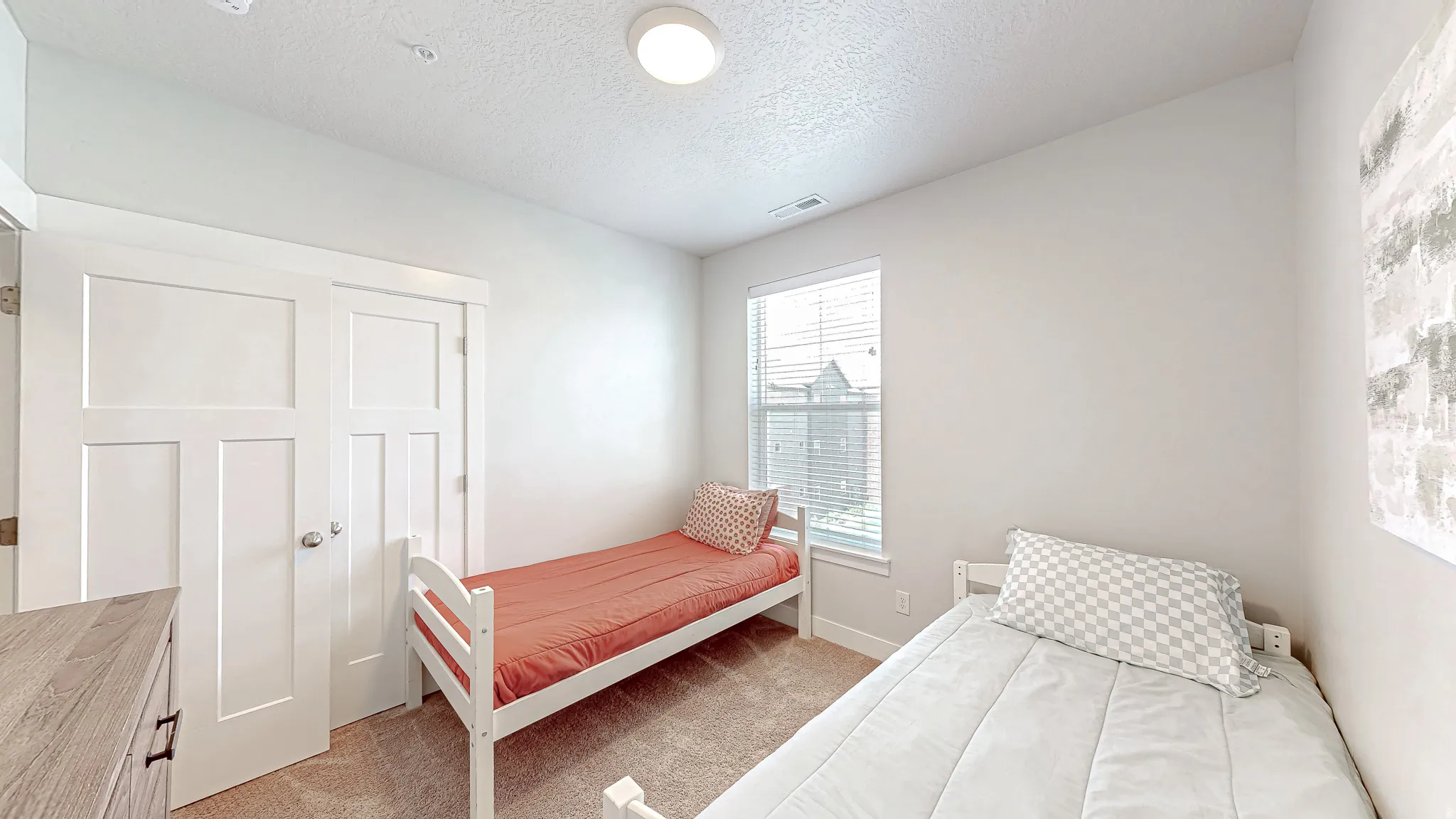 Bright room featuring a window with blinds, light-colored walls, and a textured ceiling