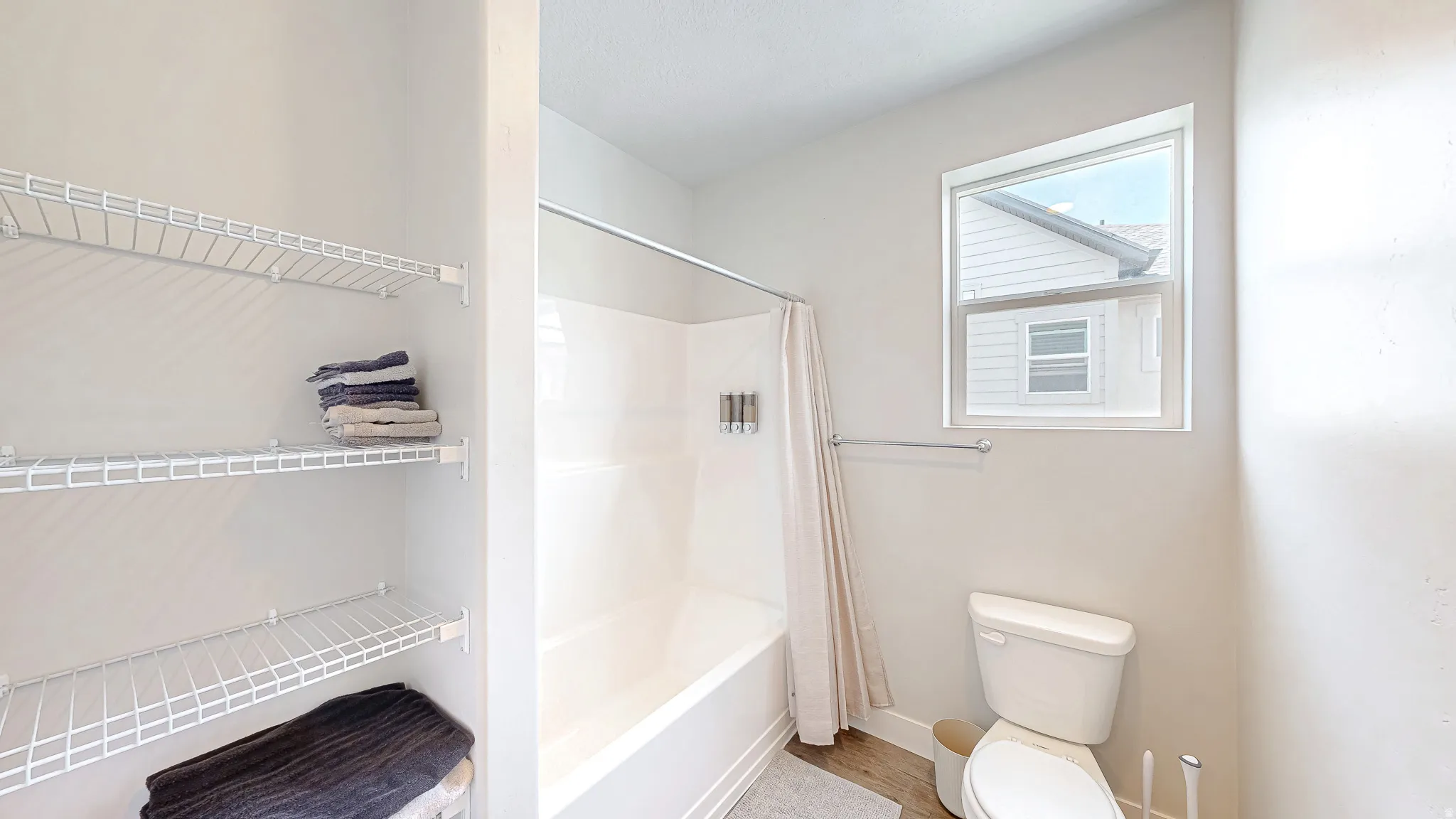 Bathroom featuring a white tub with shower, fixed showerhead, and white subway tile surround