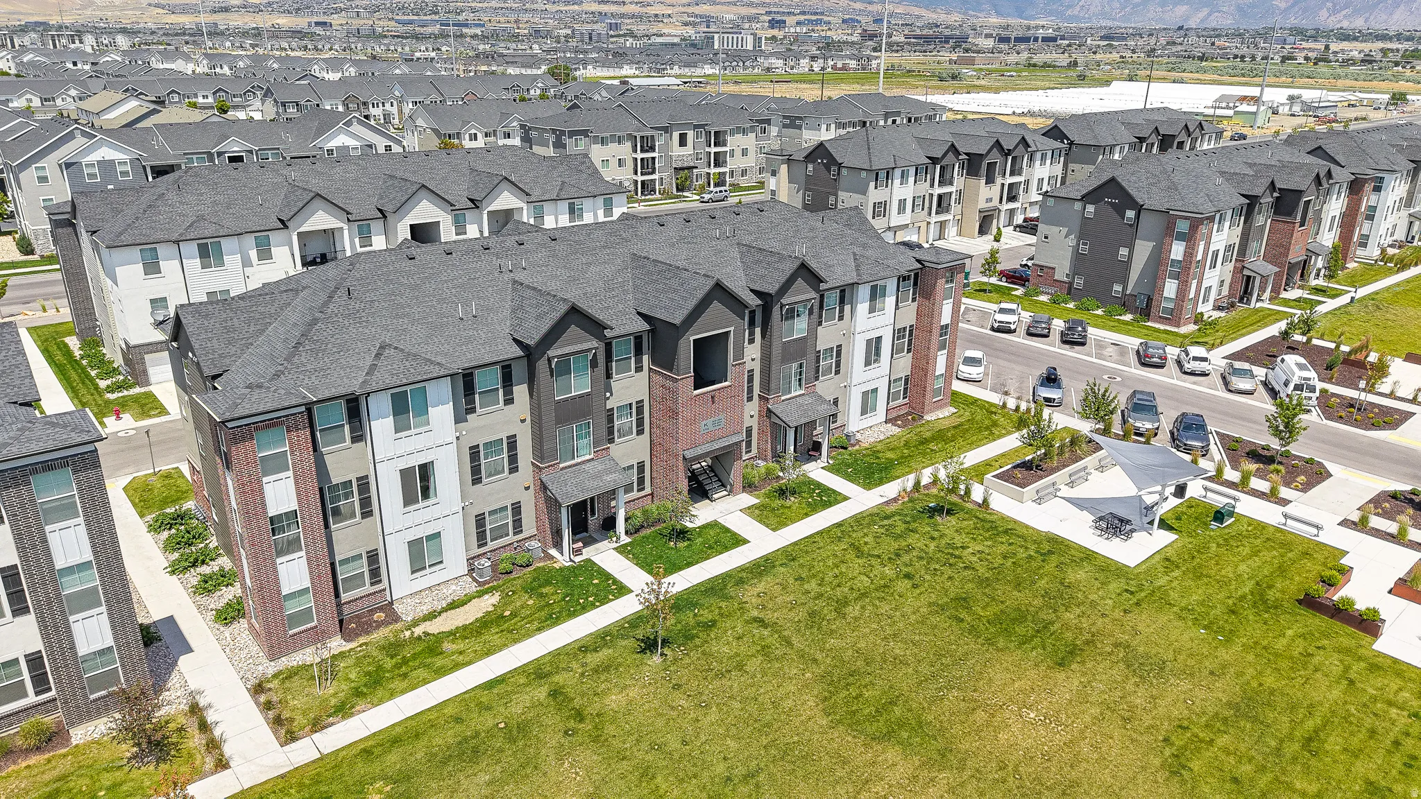 Multi-story residences featuring brick and siding exteriors with dark shingle roofs, balconies, and ground-level patios