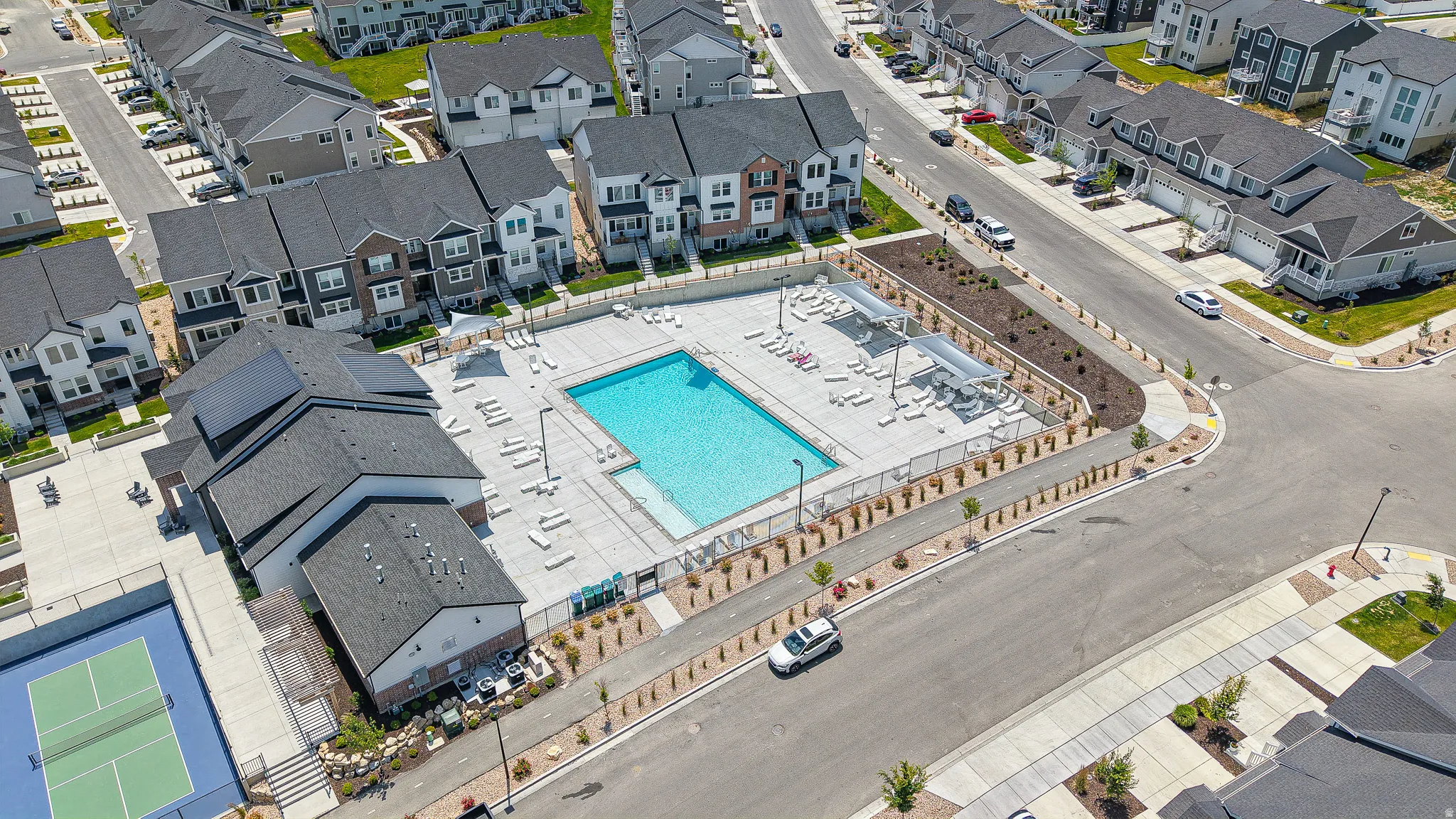Community amenities featuring an outdoor swimming pool, surrounding lounge areas, a tennis court, and a clubhouse building