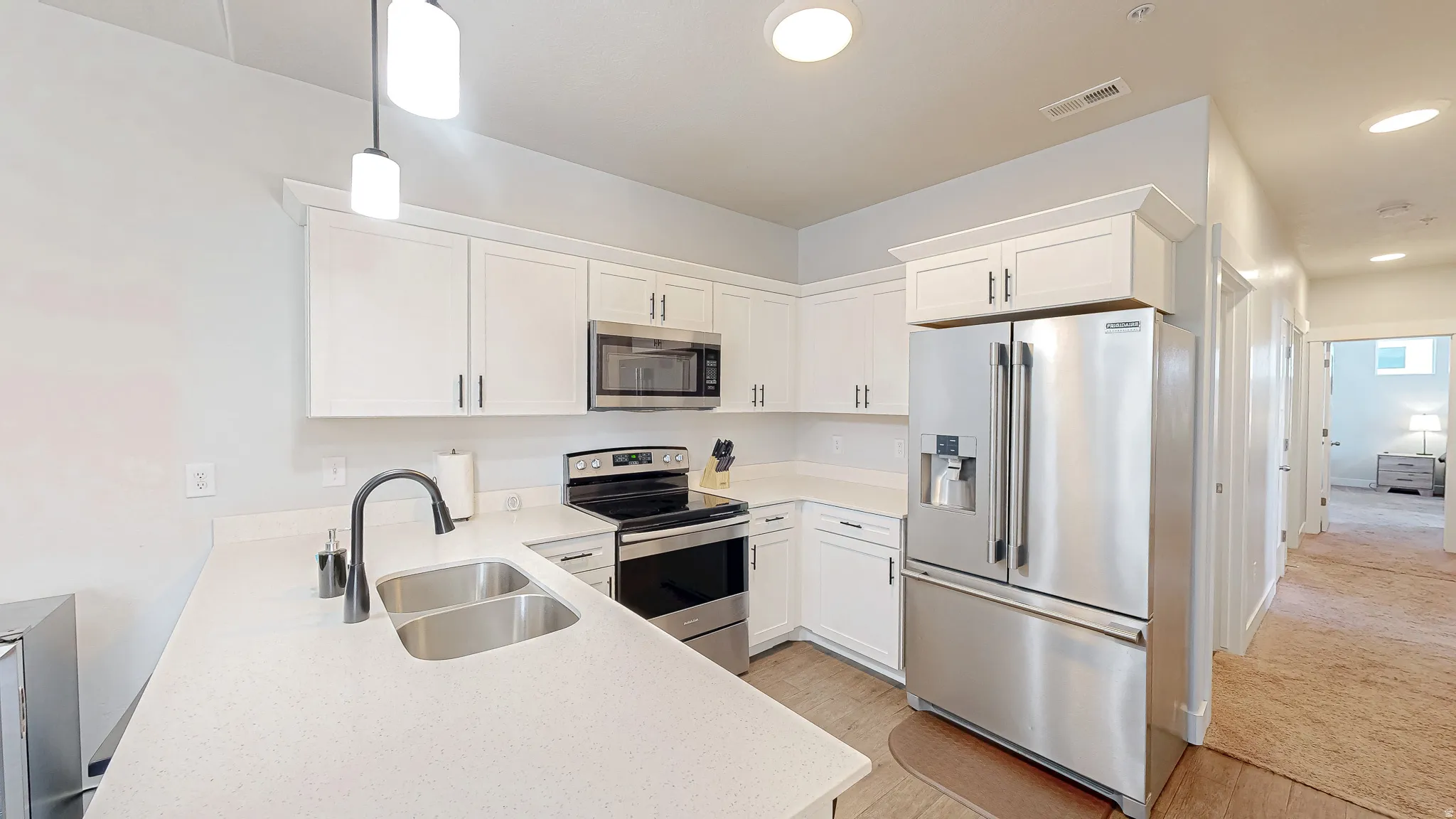 Modern kitchen featuring white cabinetry, light-toned countertops, and stainless steel appliances