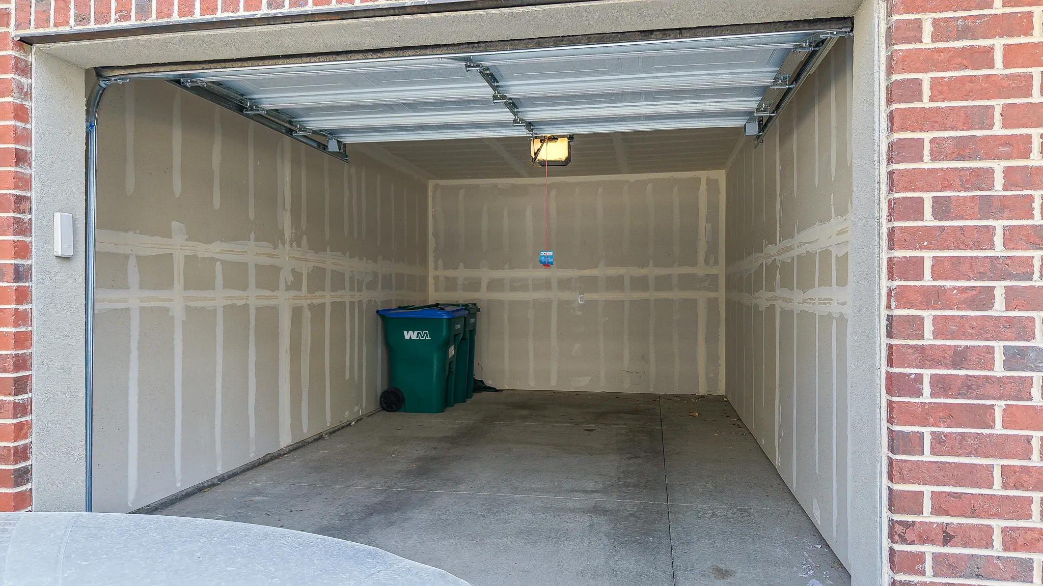 Attached garage featuring an automatic overhead door, concrete flooring, exposed drywall, and a ceiling-mounted light fixture