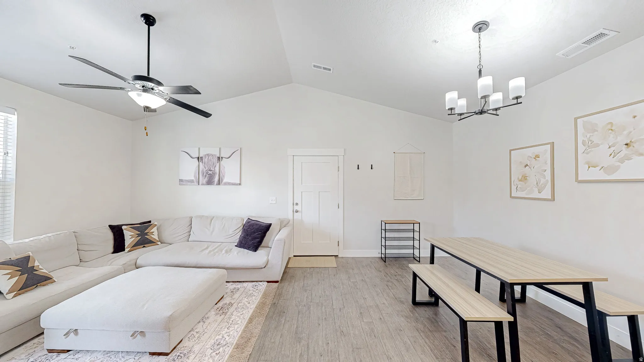 Vaulted ceiling great room featuring wood-finish flooring, a modern ceiling fan, and a contemporary chandelier