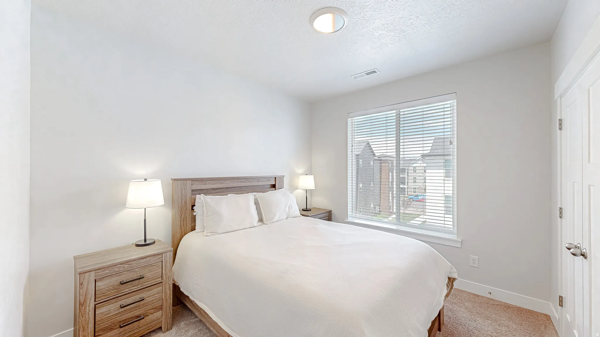 Light-filled bedroom featuring a large window with blinds, neutral wall paint, recessed ceiling lighting, and carpet flooring