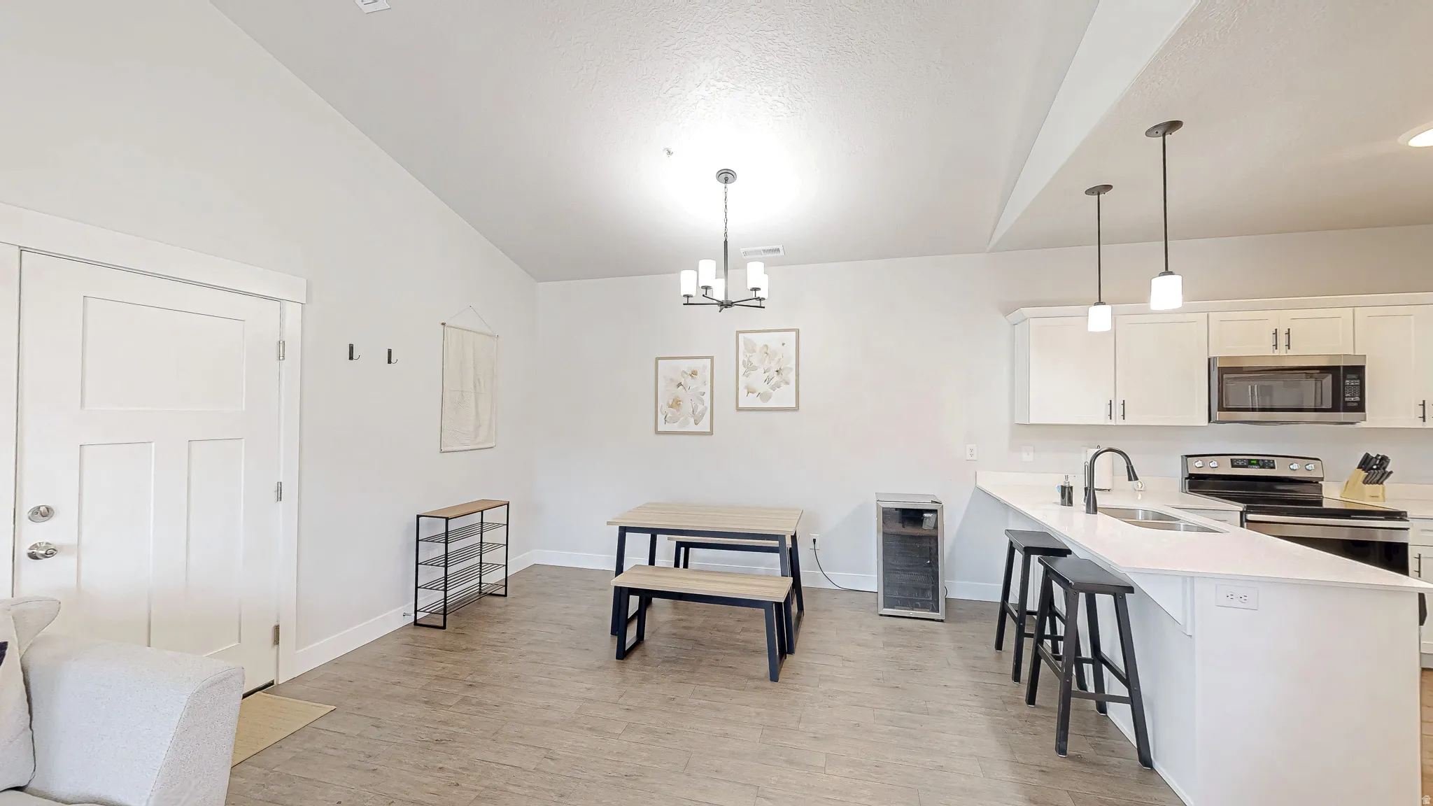 Open-concept living space featuring wood-finish flooring, white walls, and a contemporary kitchen