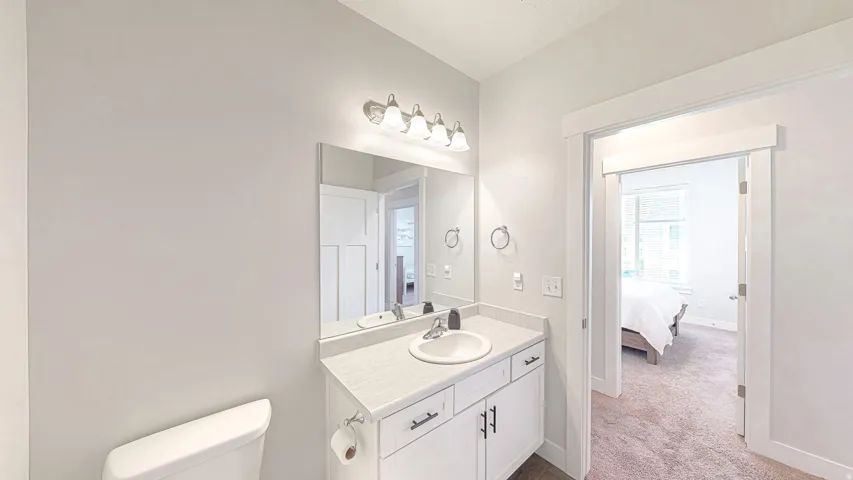 Bathroom featuring a white vanity with an integrated sink, a large wall-mounted mirror, and a three-light fixture