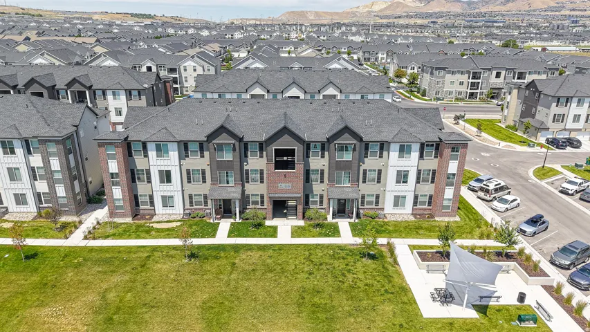 Contemporary multi-story building featuring brick and vertical siding accents, dark pitched roofs, and individual front entrances