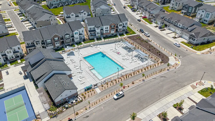 Community amenities featuring an outdoor swimming pool, surrounding lounge areas, a tennis court, and a clubhouse building