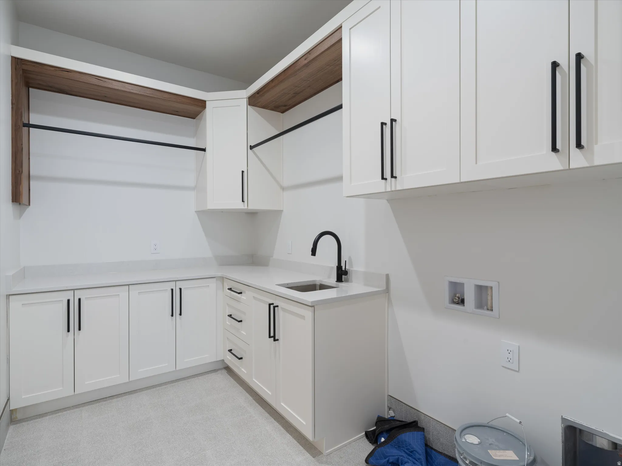 Utility room featuring extensive white cabinetry, light-toned countertops, and a black gooseneck faucet