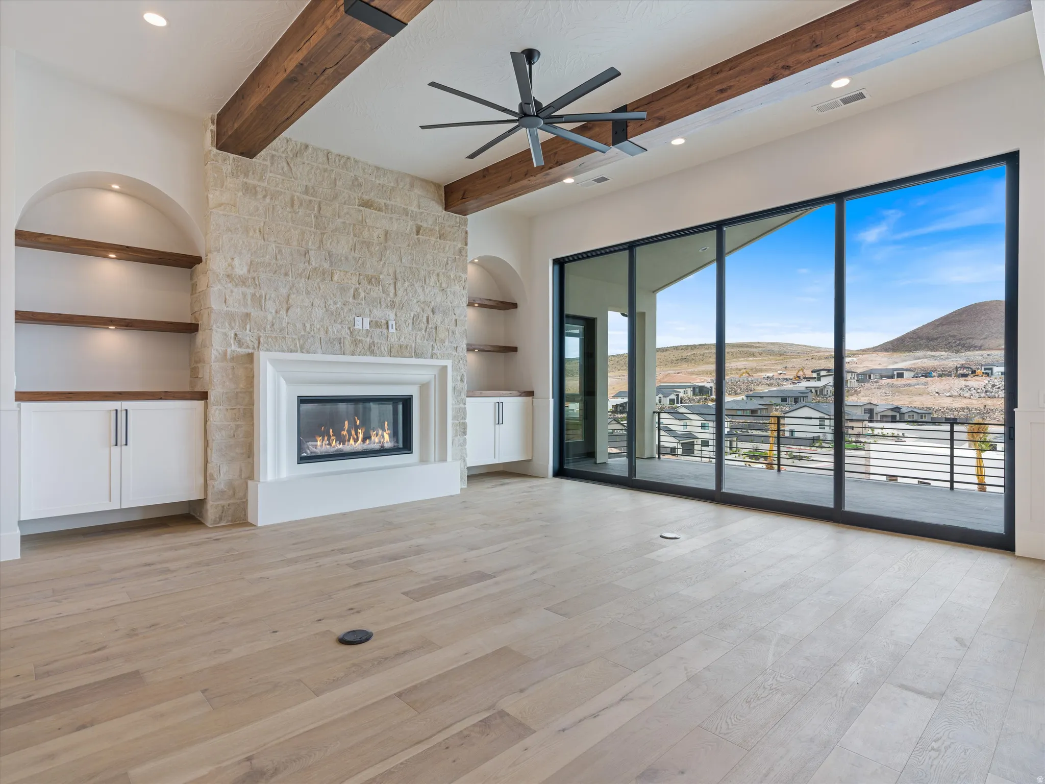 Spacious interior featuring a stone fireplace with a white mantel, built-in cabinetry with integrated shelving, and wood-finish flooring