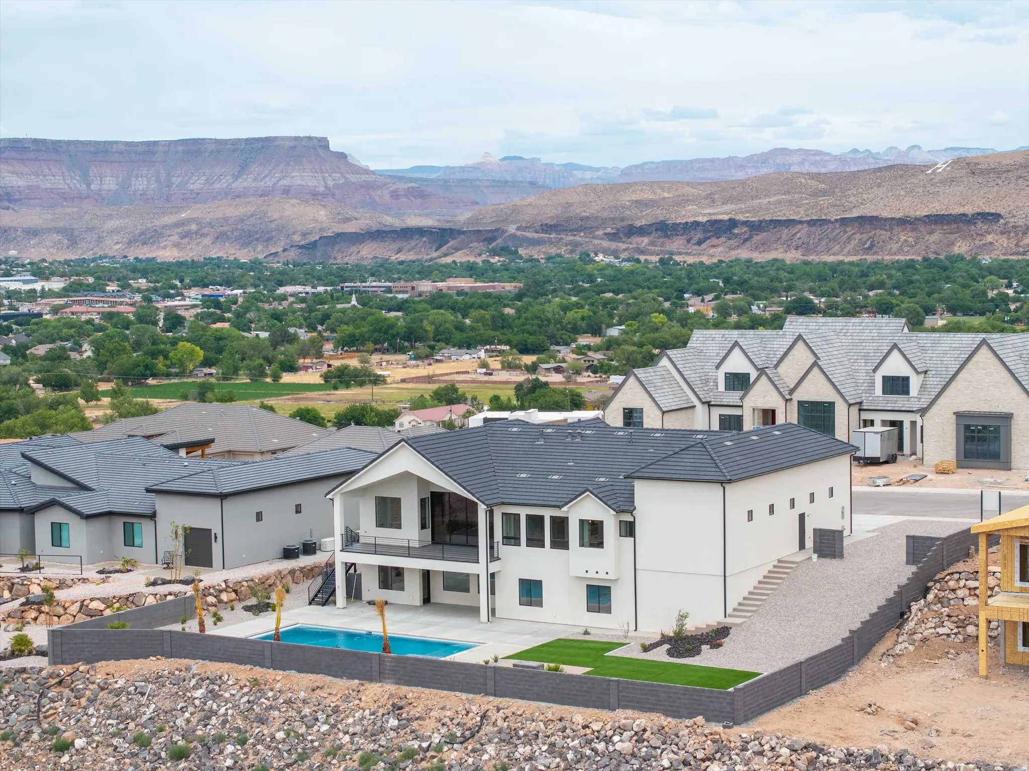 Modern stucco exterior with dark tile roofing and a spacious rear balcony