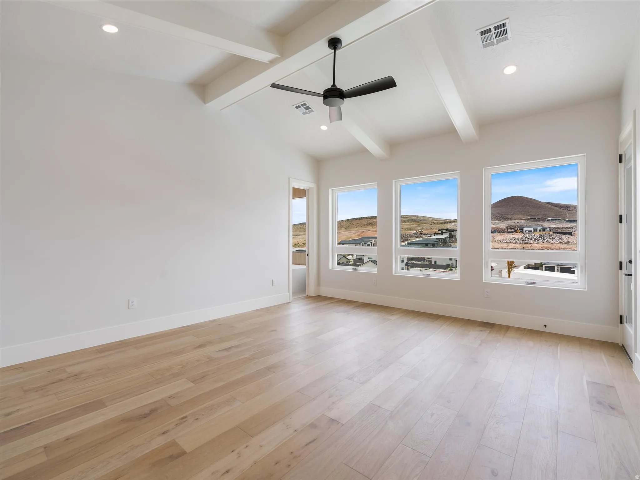 Spacious room featuring vaulted ceilings with exposed beams, recessed lighting, and a modern ceiling fan
