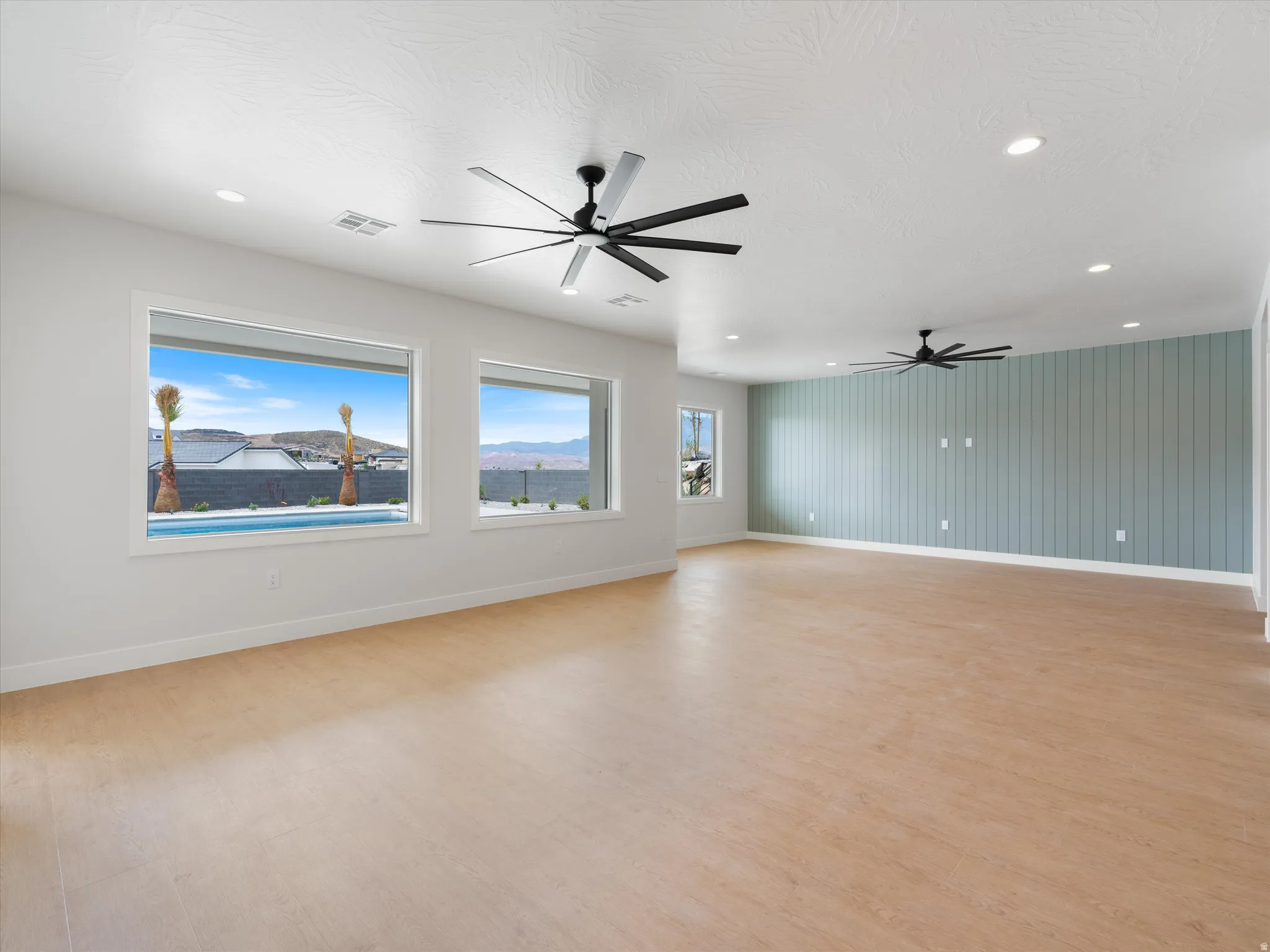 Expansive interior space featuring wood-finish flooring, recessed lighting, and modern ceiling fans