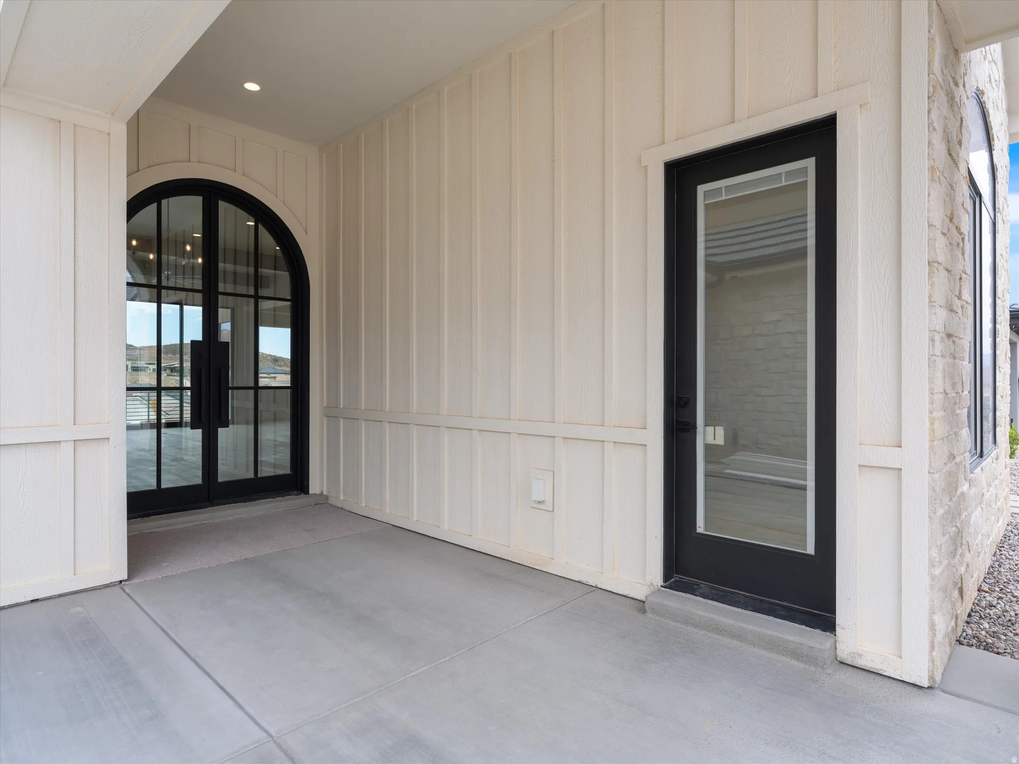 Arched double-door entryway with black frames and clear glass panels