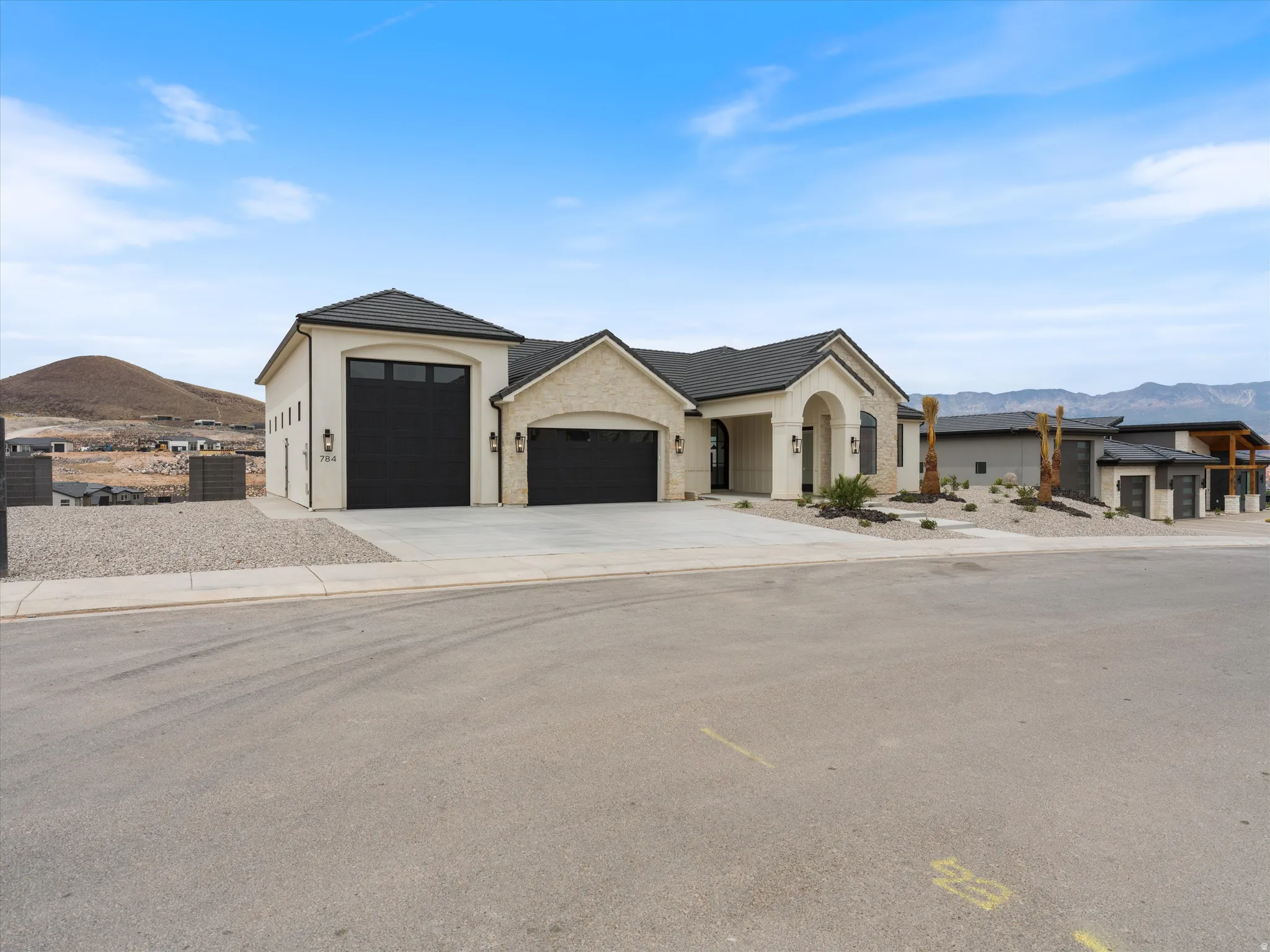 Contemporary stucco and stone-clad exterior with a dark shingle roof