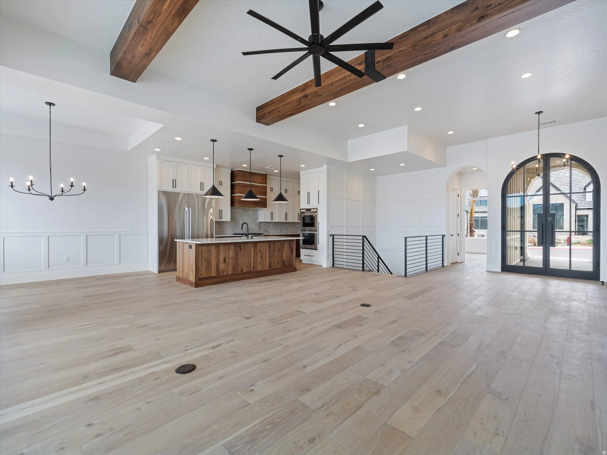 Spacious living area featuring light wood-finish flooring and exposed wood ceiling beams