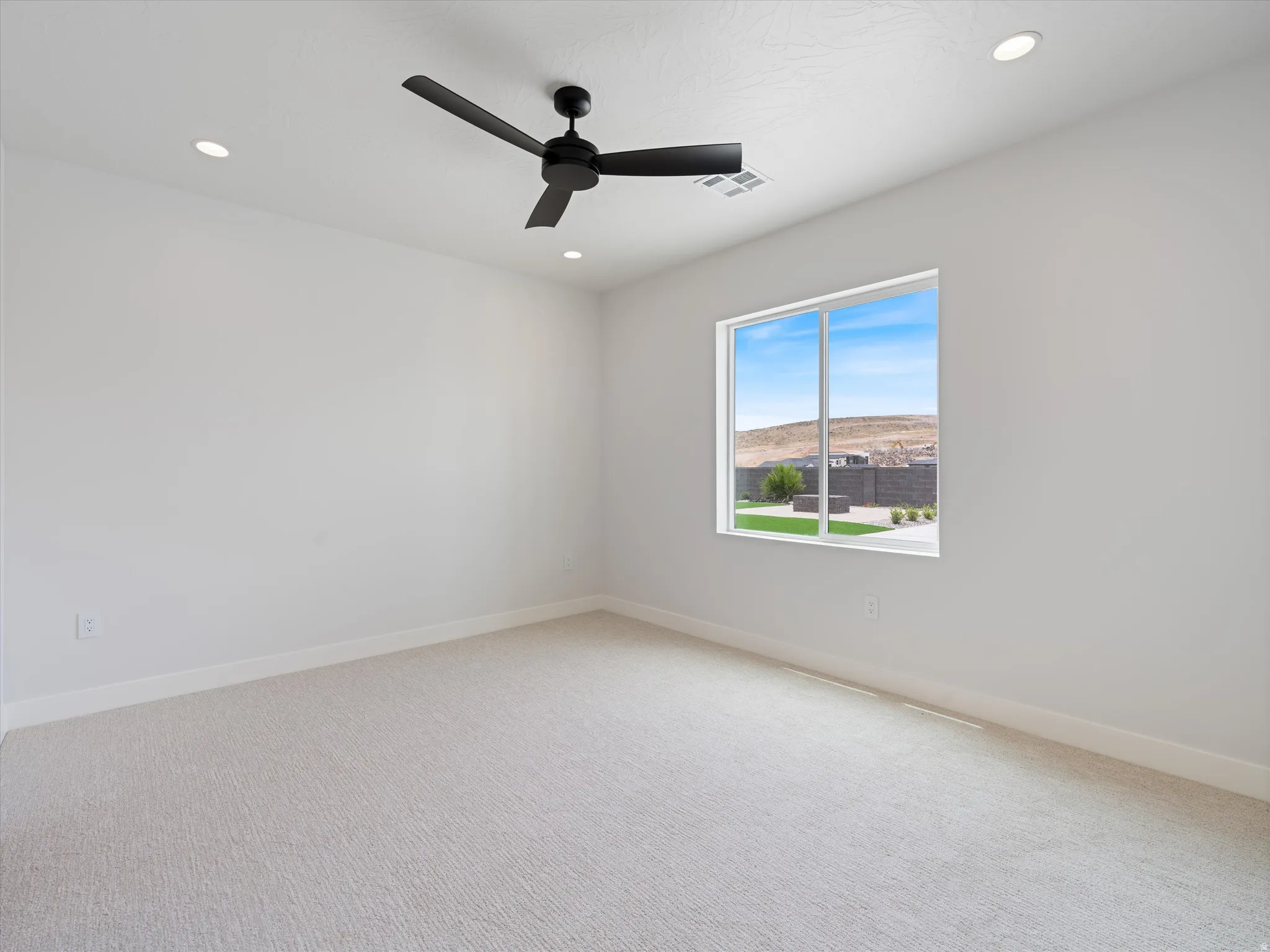 Bright room featuring a large window, recessed lighting, a ceiling fan, light-toned carpet, and clean white walls