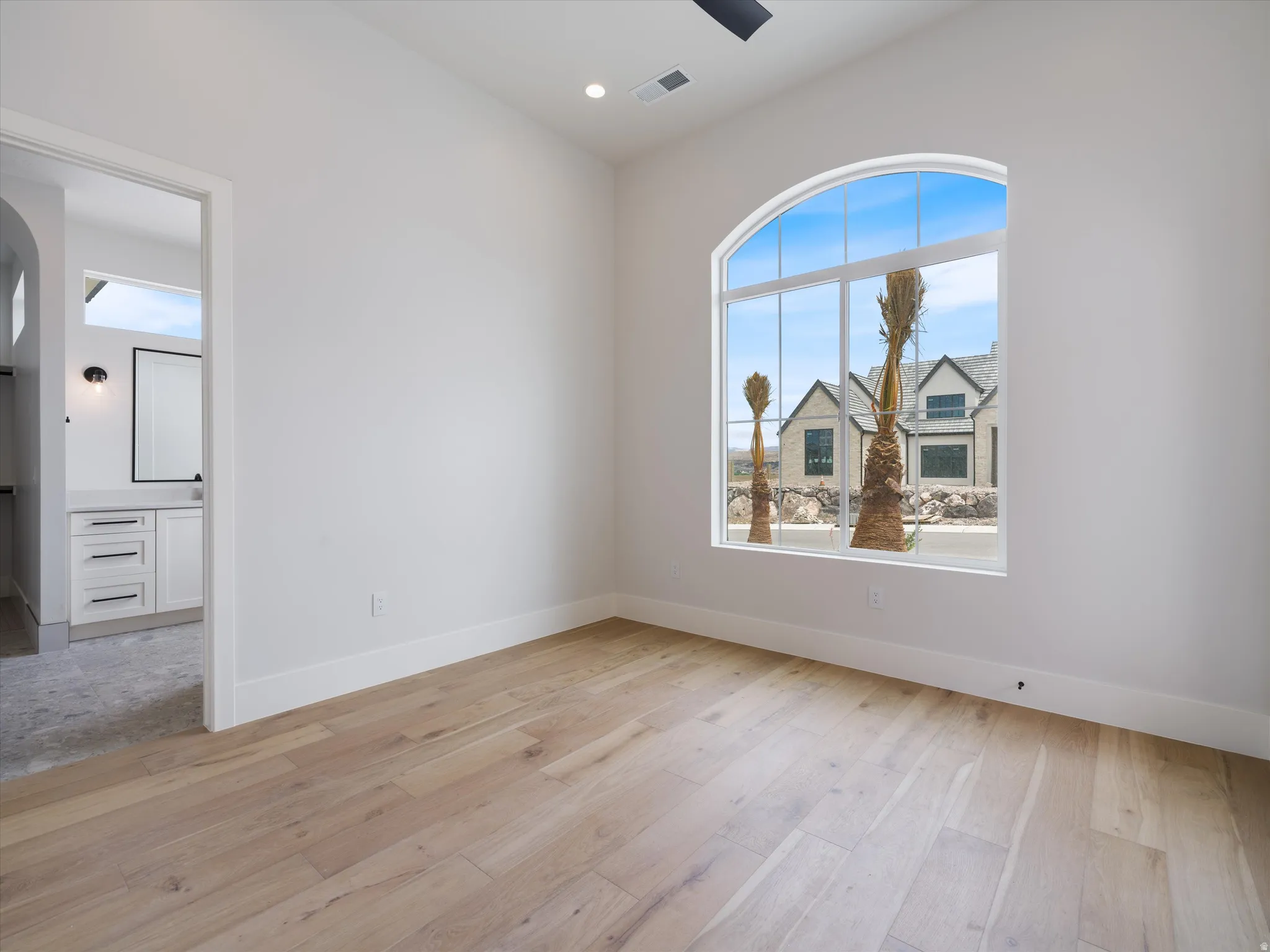 Room featuring light wood-finish flooring and a prominent arched window