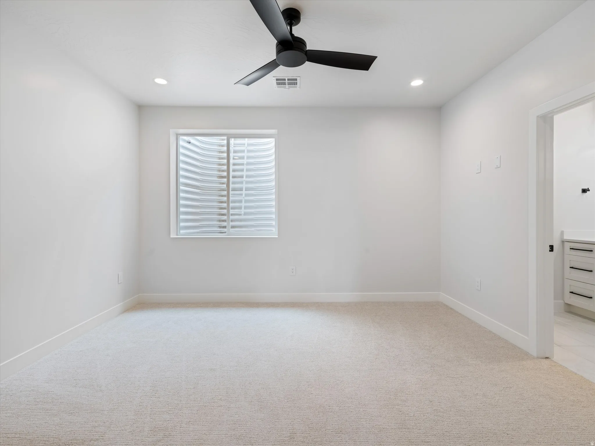 Carpeted room with a black ceiling fan, recessed lighting, and a window with a white frame