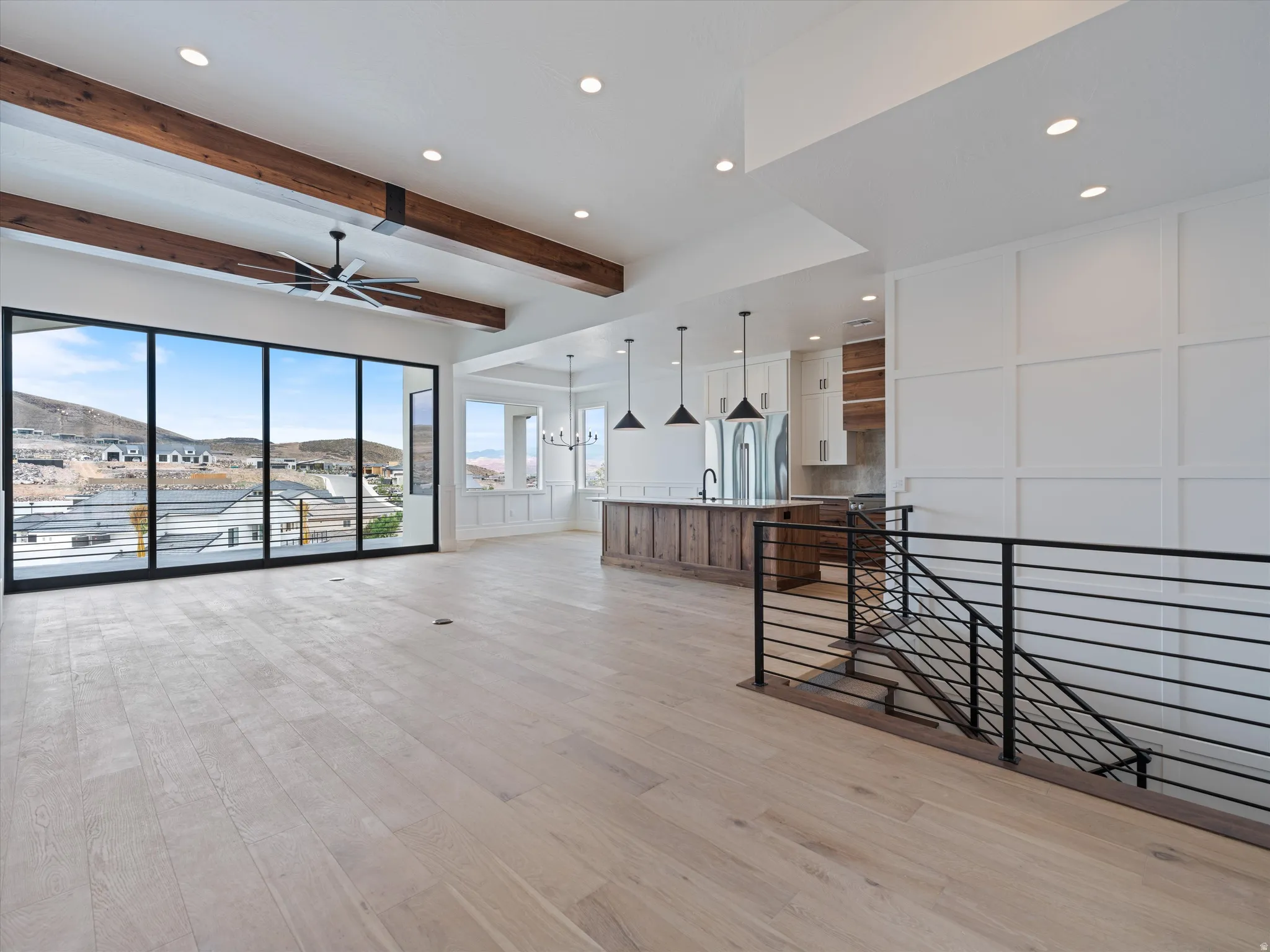 Spacious open-concept interior featuring wood-finish flooring, exposed ceiling beams, and a large multi-panel sliding glass door