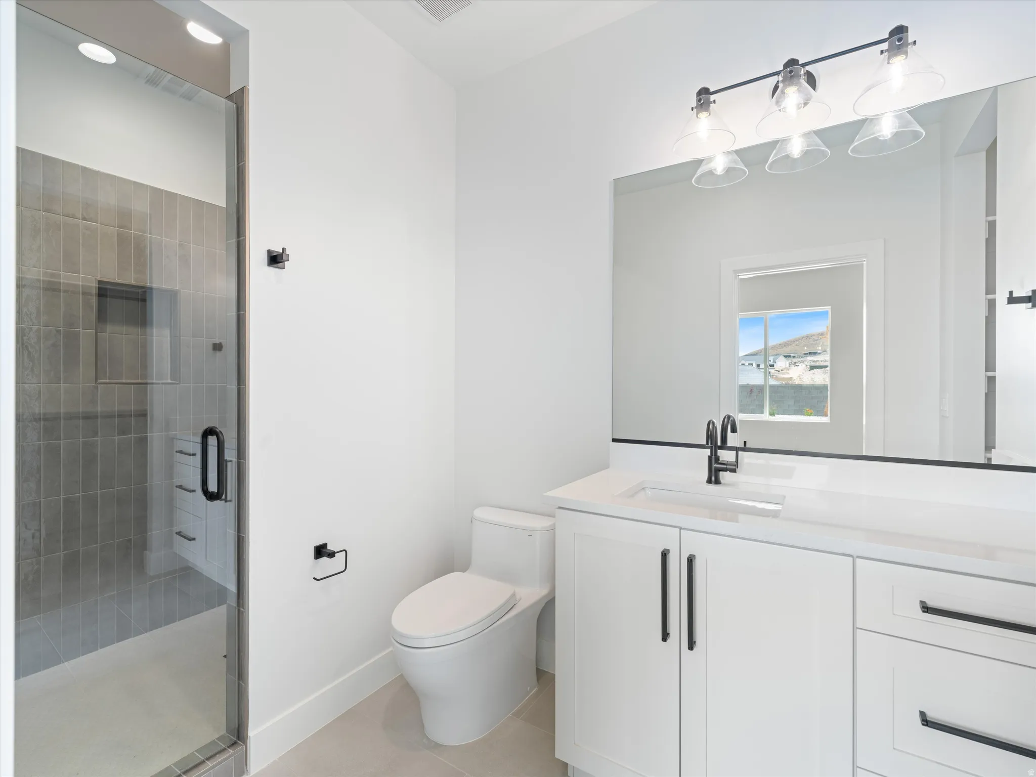 Bathroom featuring a walk-in shower with vertical tile, a frameless glass enclosure, and a built-in shower niche