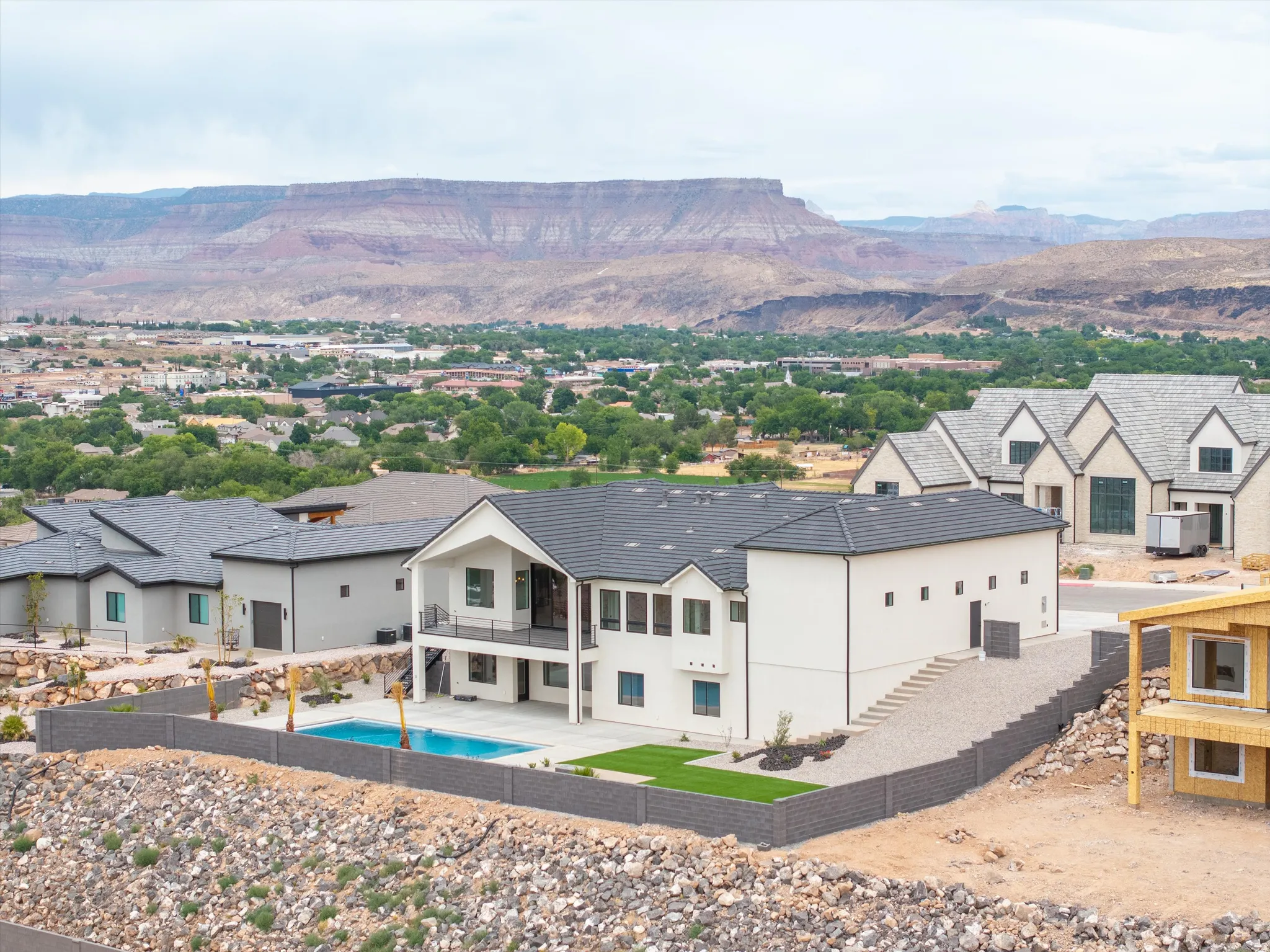 Contemporary home featuring a private swimming pool, expansive paved patio, turf grass area, and a second-story balcony