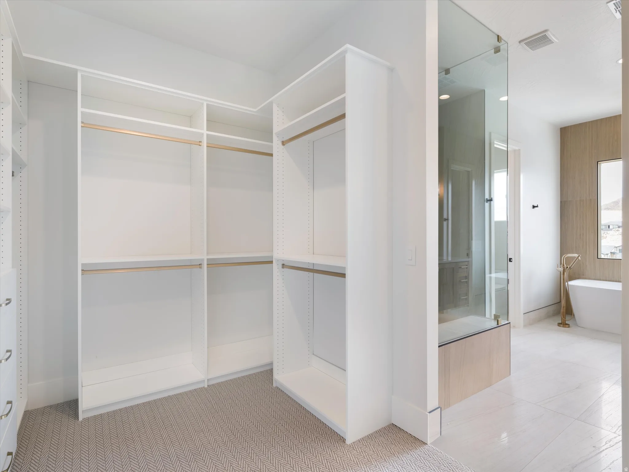 Custom closet system featuring white built-in shelving, hanging rods, and a herringbone pattern carpet