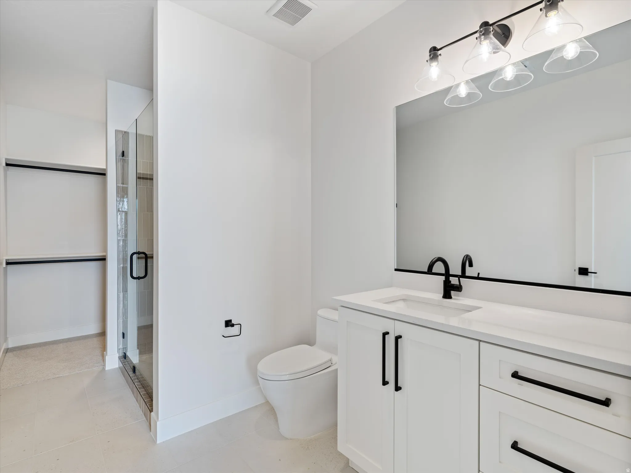 Bathroom vanity with white cabinetry, quartz countertop, and matte black fixtures