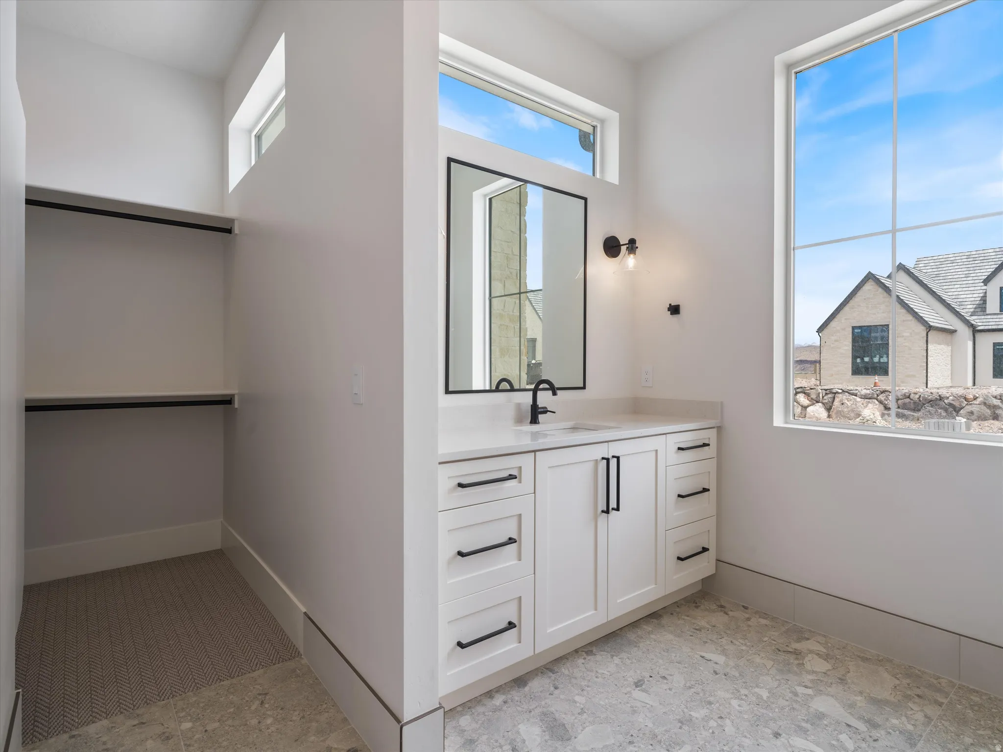 Vanity with white shaker cabinetry, black hardware, and a light-toned countertop