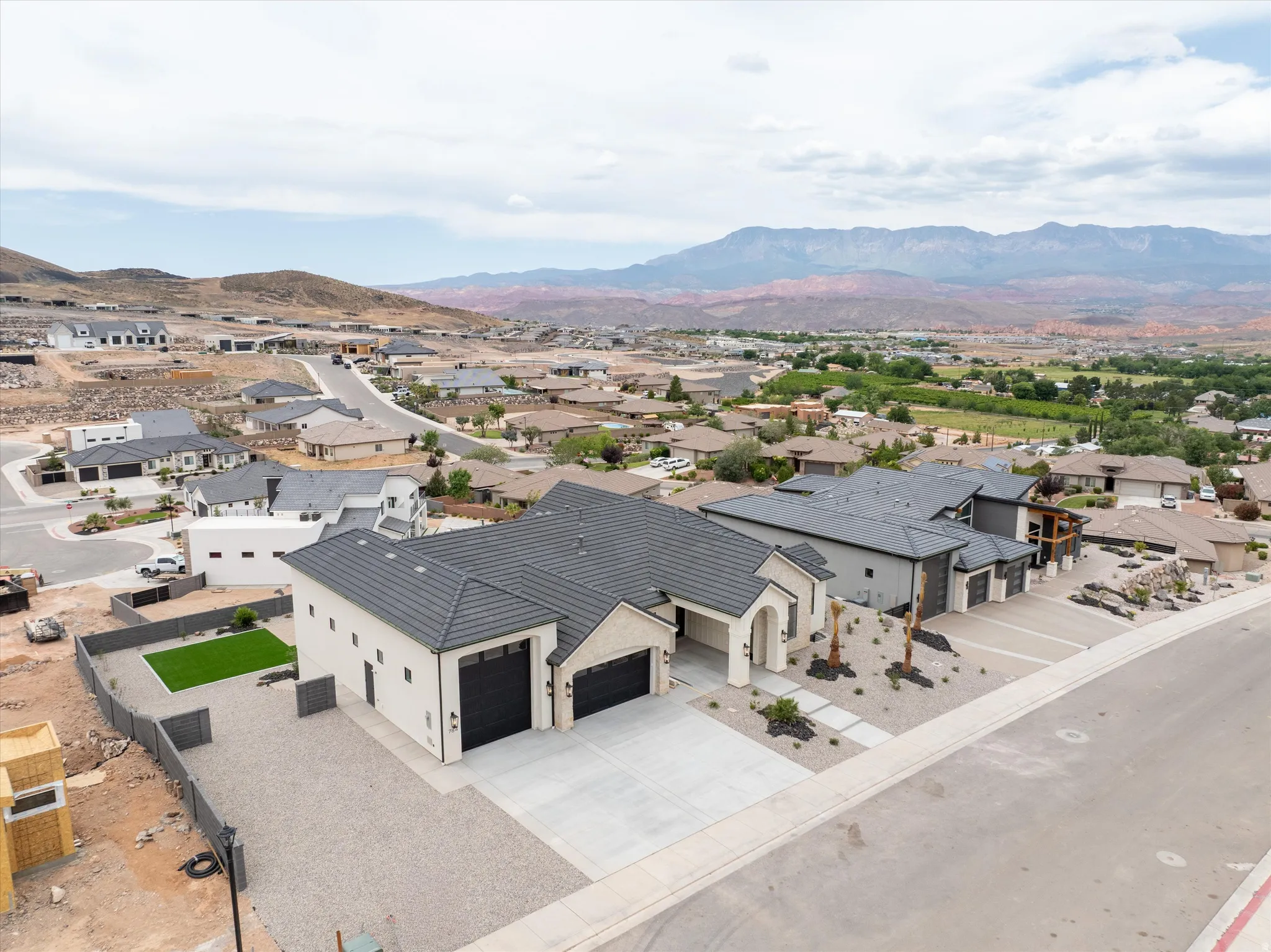 Contemporary residence featuring a light-toned exterior, dark tile roofing, and multiple garage doors