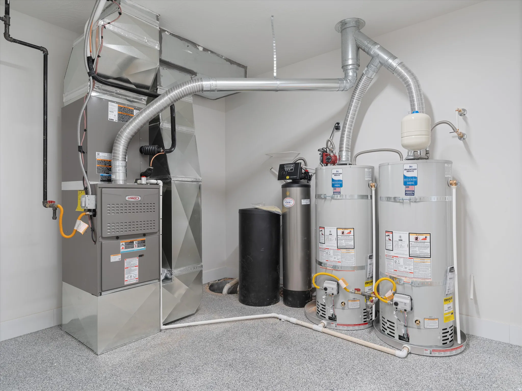 Utility space featuring a furnace, two water heaters, a water softener, and a water filtration system