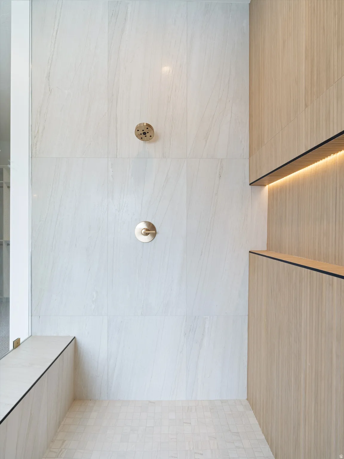 Contemporary shower space featuring large format white tiled walls and a mosaic tiled floor