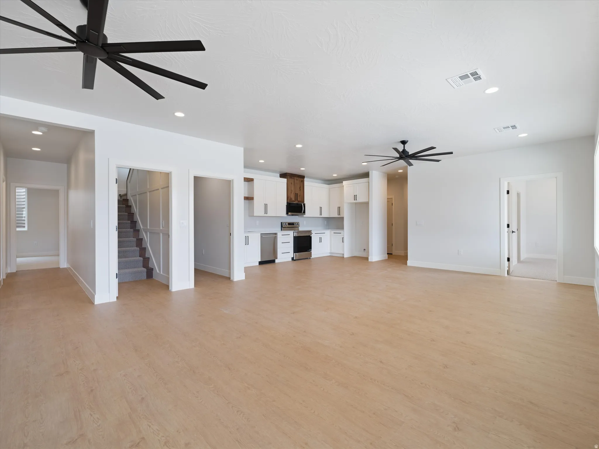 Open-concept living space featuring wood-finish flooring, recessed lighting, and modern ceiling fans
