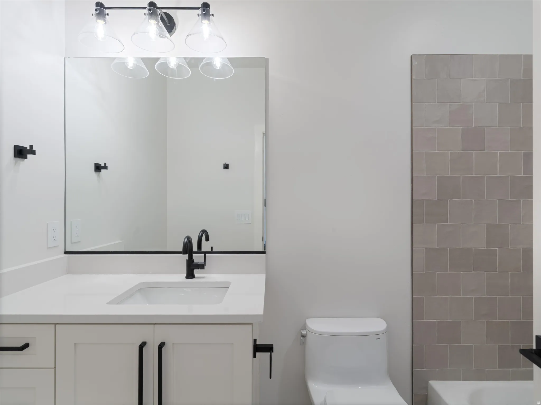 Modern bathroom vanity with a white countertop, undermount sink, and matte black faucet